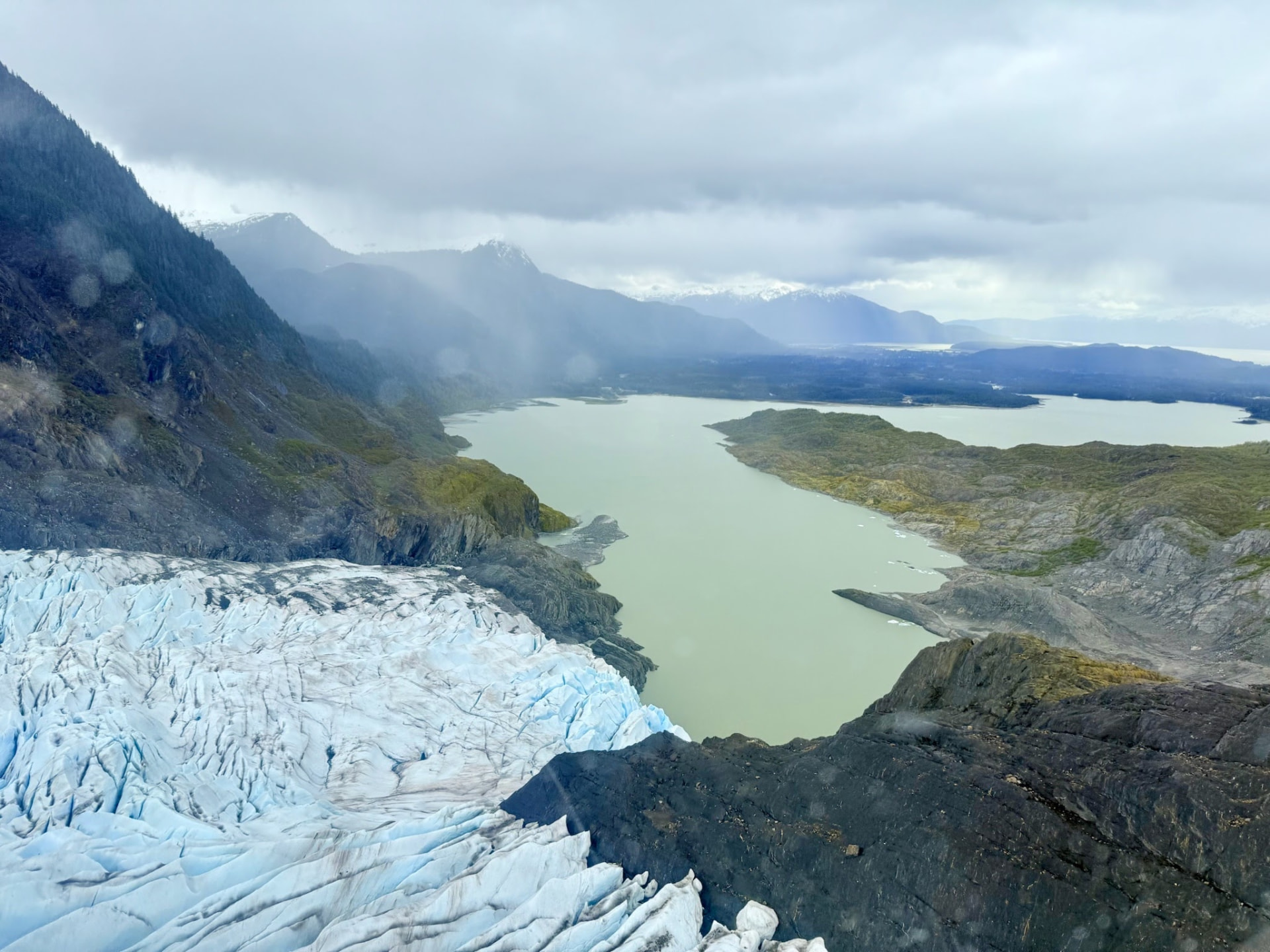 Aerial view of a glacier meeting a lake in a valley