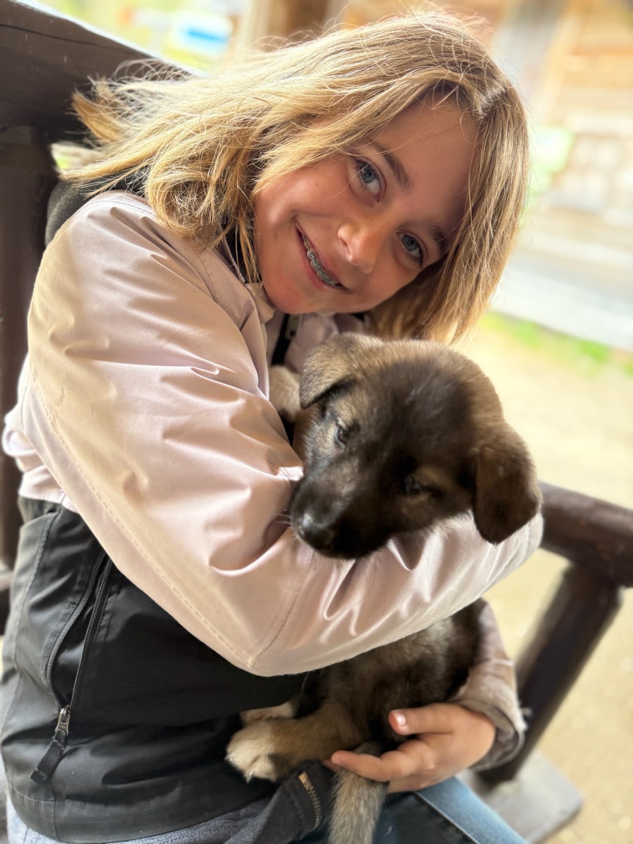 Young girl smiling while hugging a dark brown puppy