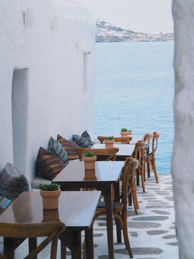 A whitewashed terrace with tables above the sea on Mykonos