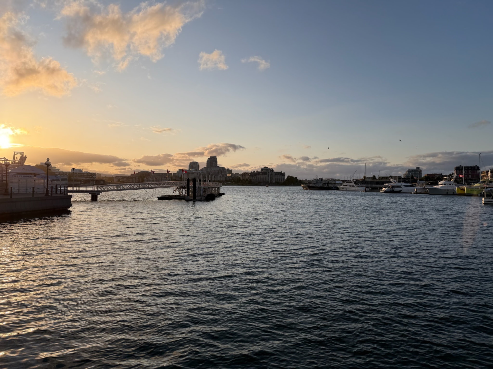 Sunset over Victoria harbor with boats and buildings reflected in the water