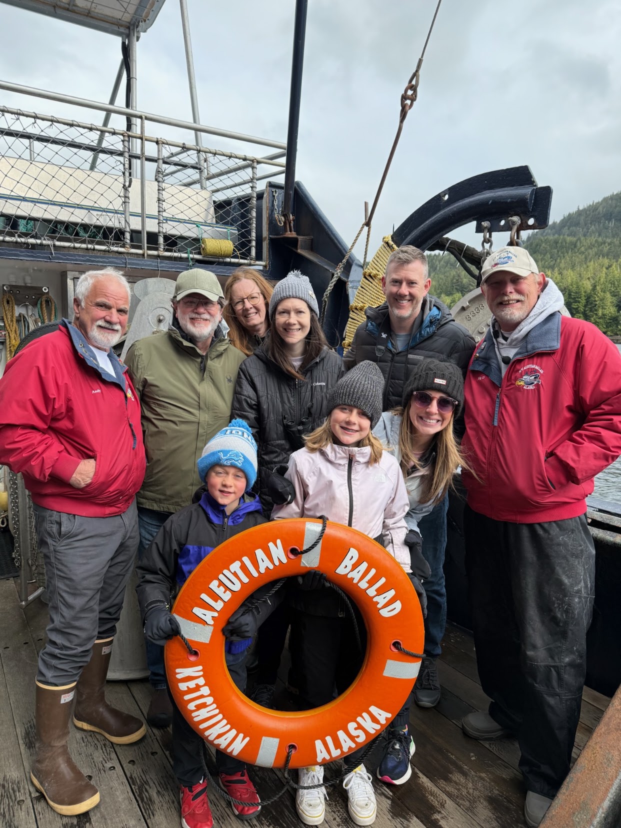 Family posing with two crew members on a crab boat