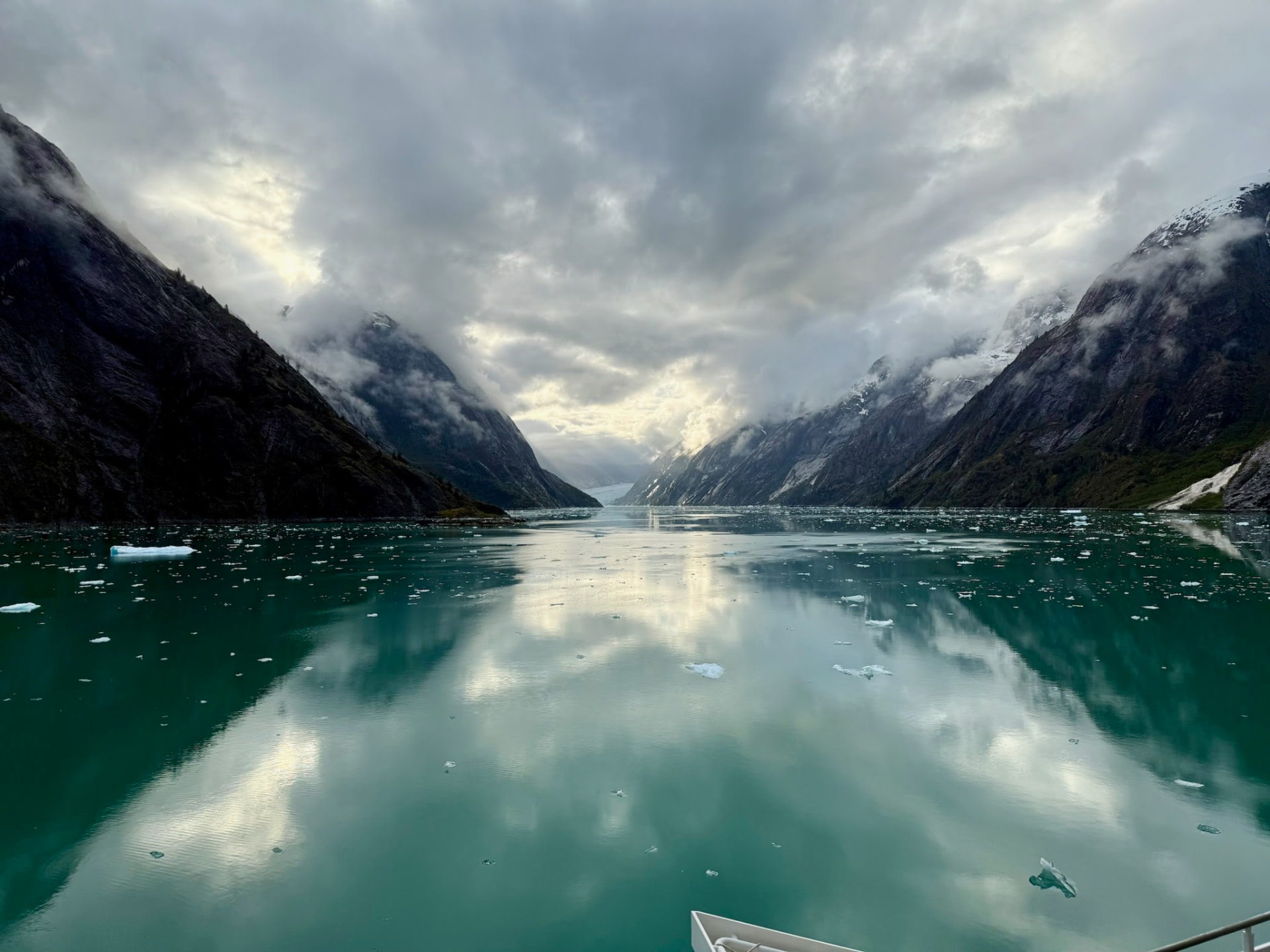 Clouds and mountains reflected in glassy water at dawn